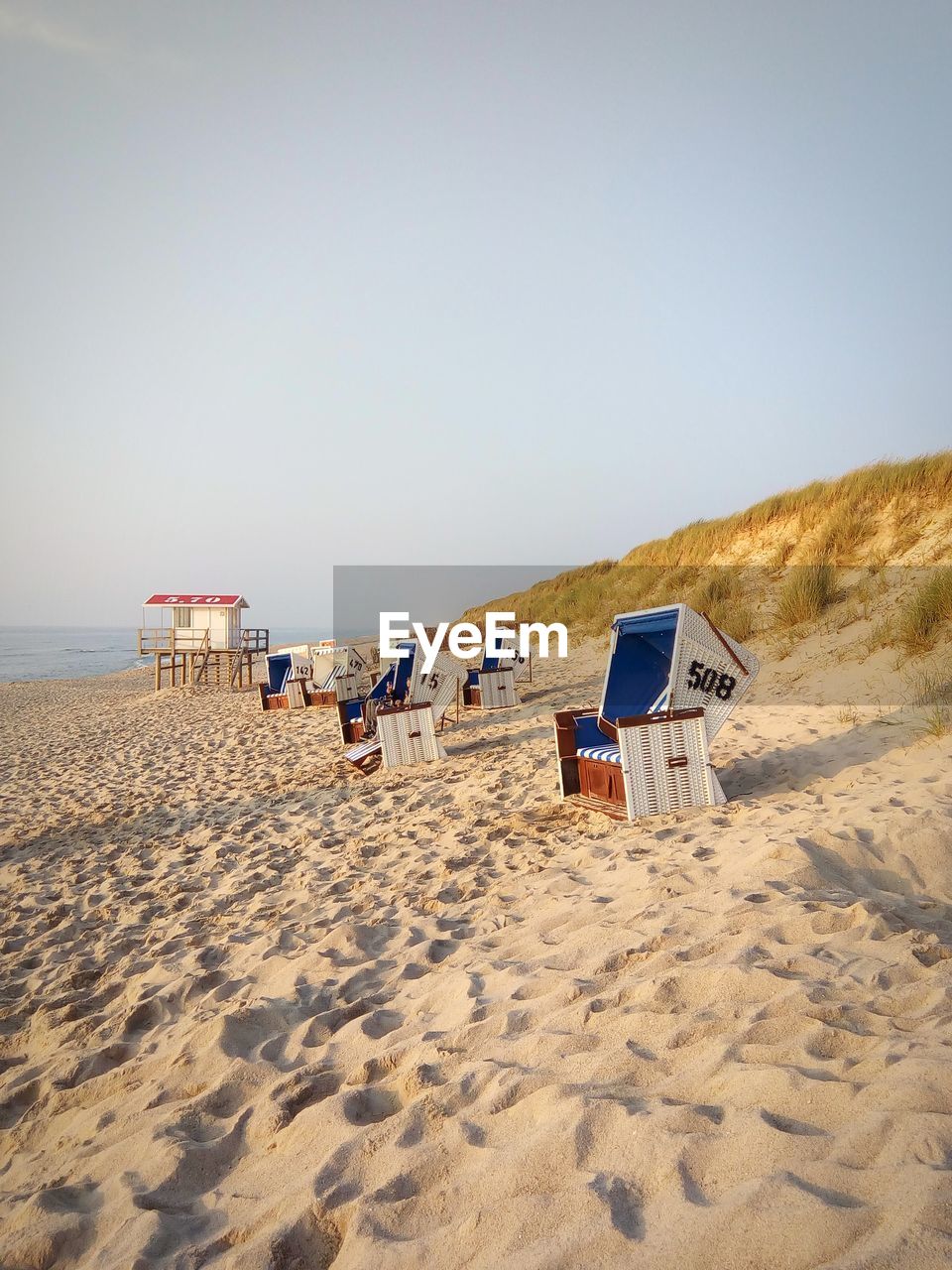 HOODED BEACH CHAIRS ON SAND AGAINST SKY