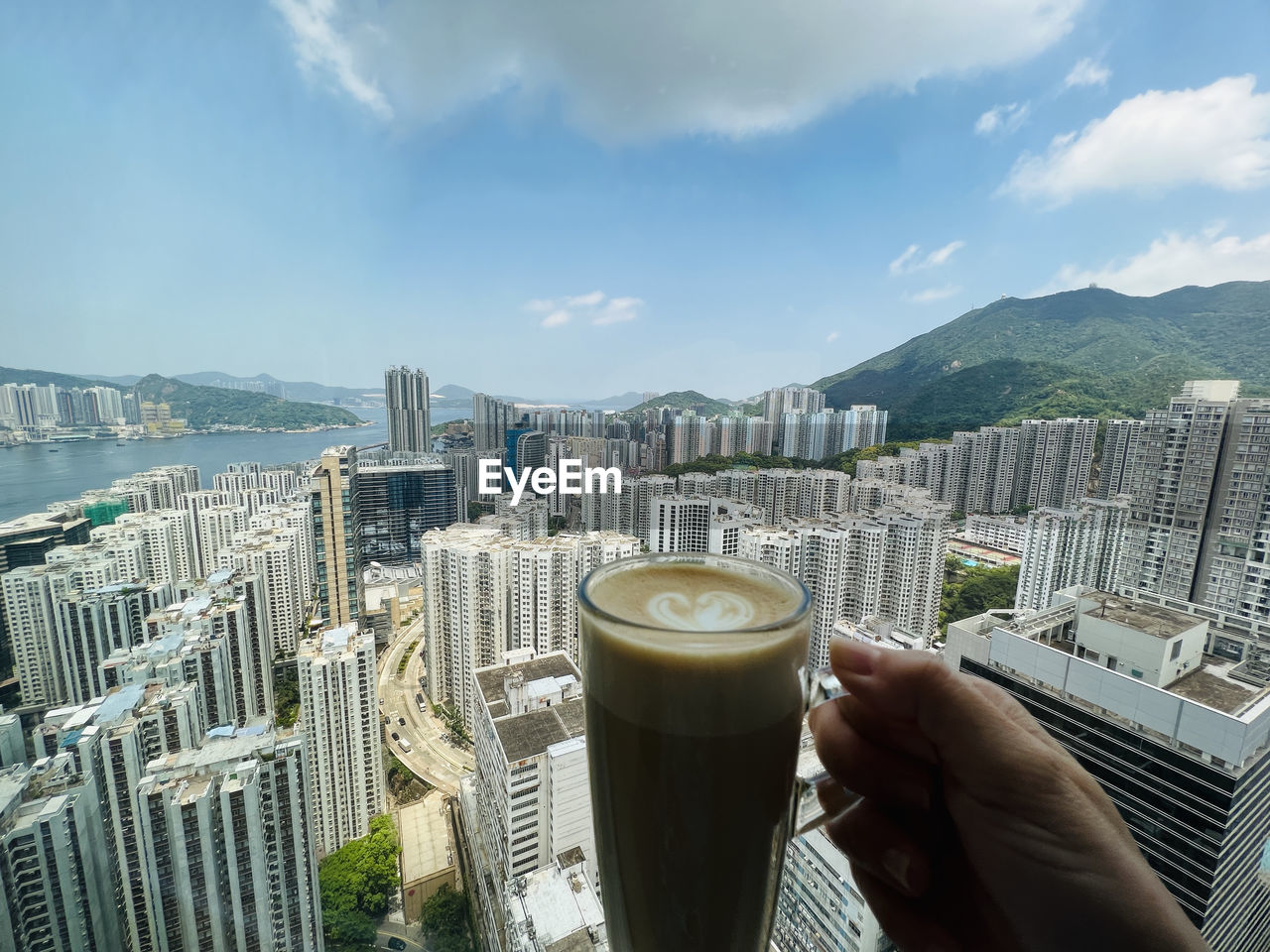 Drinking coffee while enjoying high angle view of cityscape against sky