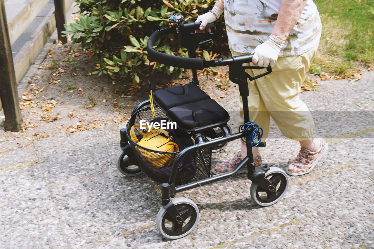 Low section of senior woman with rollator walking on footpath