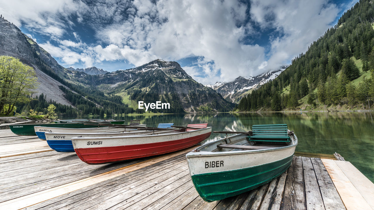 BOATS MOORED ON LAKE AGAINST SKY