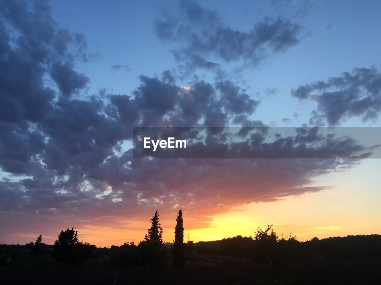 Silhouette landscape against dramatic sky during sunset