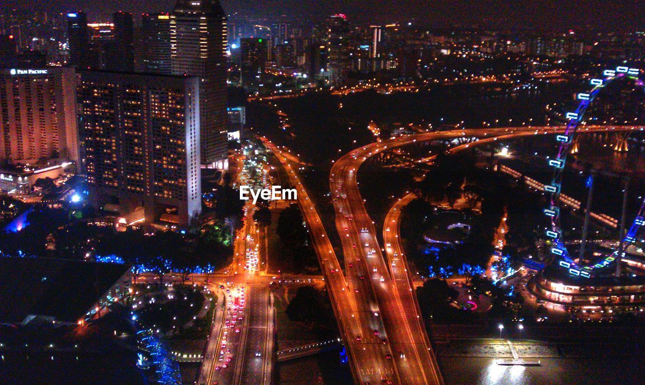 High angle view of multiple lane highway and illuminated buildings in city