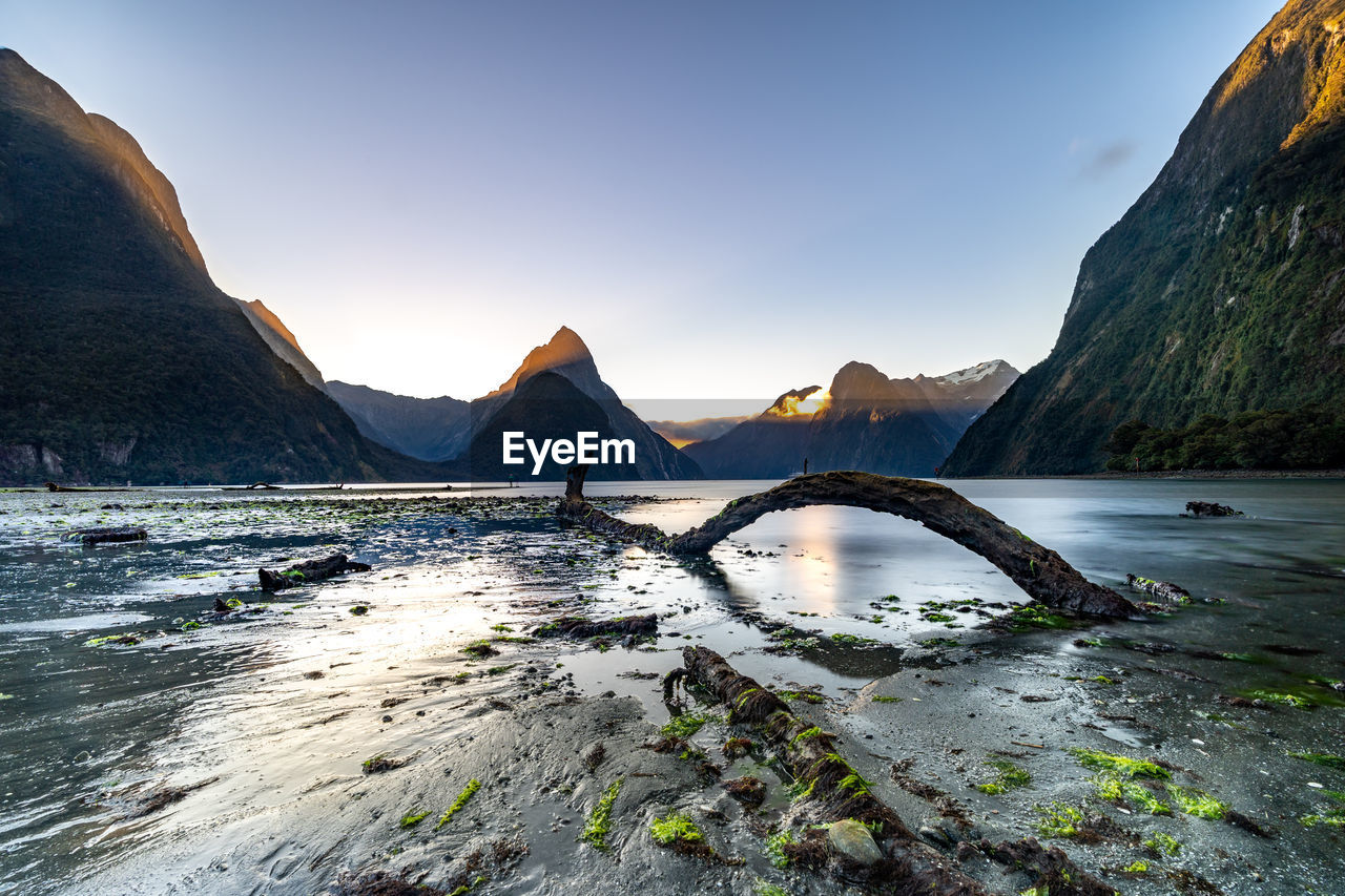 Scenic view of lake by mountains against sky during sunset