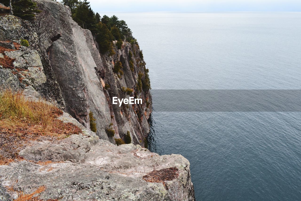 ROCK FORMATIONS ON SEA SHORE AGAINST SKY