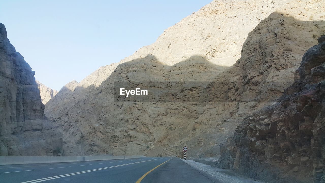 ROAD PASSING THROUGH ROCKS AGAINST CLEAR SKY