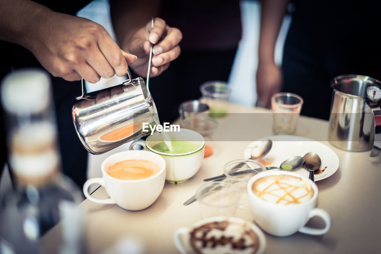 High angle view of barista mixing milk in drink at cafe