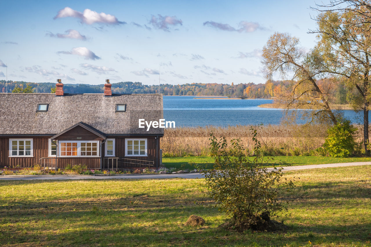 architecture, built structure, building exterior, building, sky, house, rural area, water, plant, nature, grass, landscape, residential district, estate, tree, cloud, rural scene, land, scenics - nature, no people, autumn, travel destinations, environment, blue, outdoors, beauty in nature, farm, day, home, mansion, lake, travel, tranquility, sunlight, tourism, non-urban scene, farmhouse