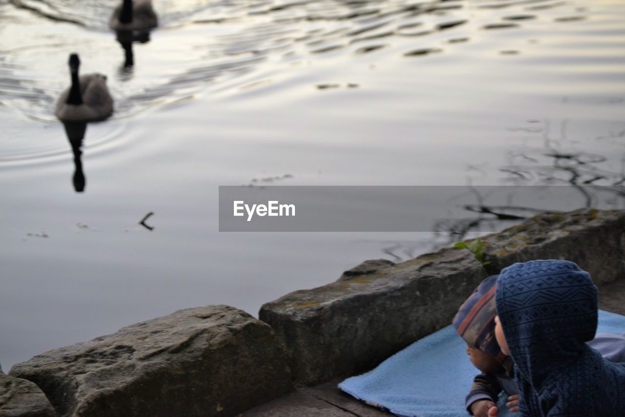 REAR VIEW OF WOMAN SWIMMING ON LAKE