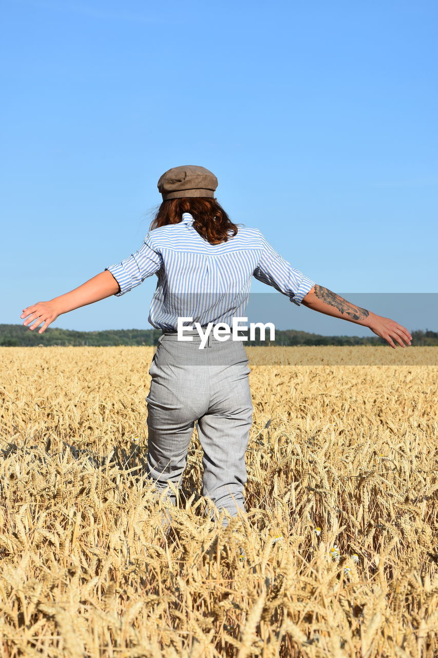 WOMAN STANDING ON FIELD AGAINST CLEAR SKY