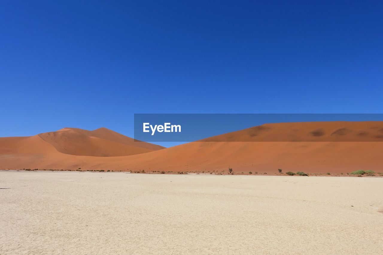 Scenic view of desert against clear blue sky