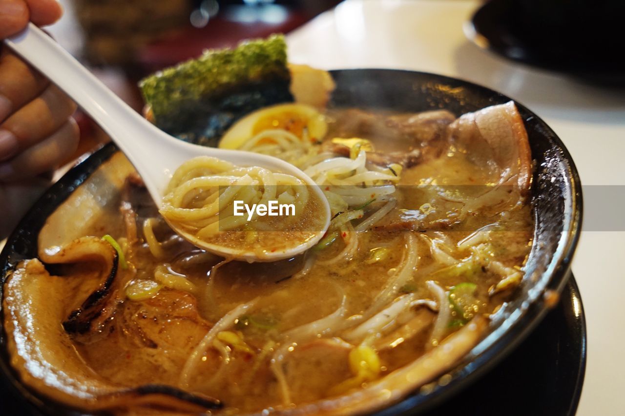 Cropped image of person having ramen noodle soup