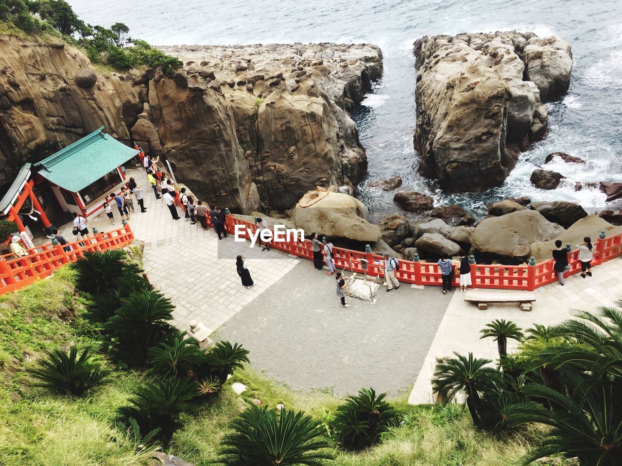 HIGH ANGLE VIEW OF PEOPLE ON ROCK FORMATION BY SEA