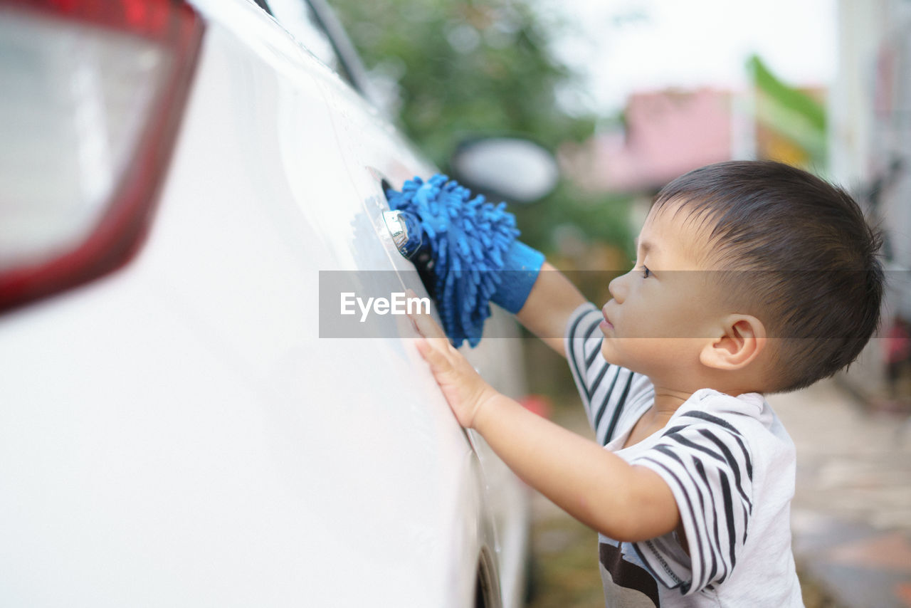 Cute boy cleaning car