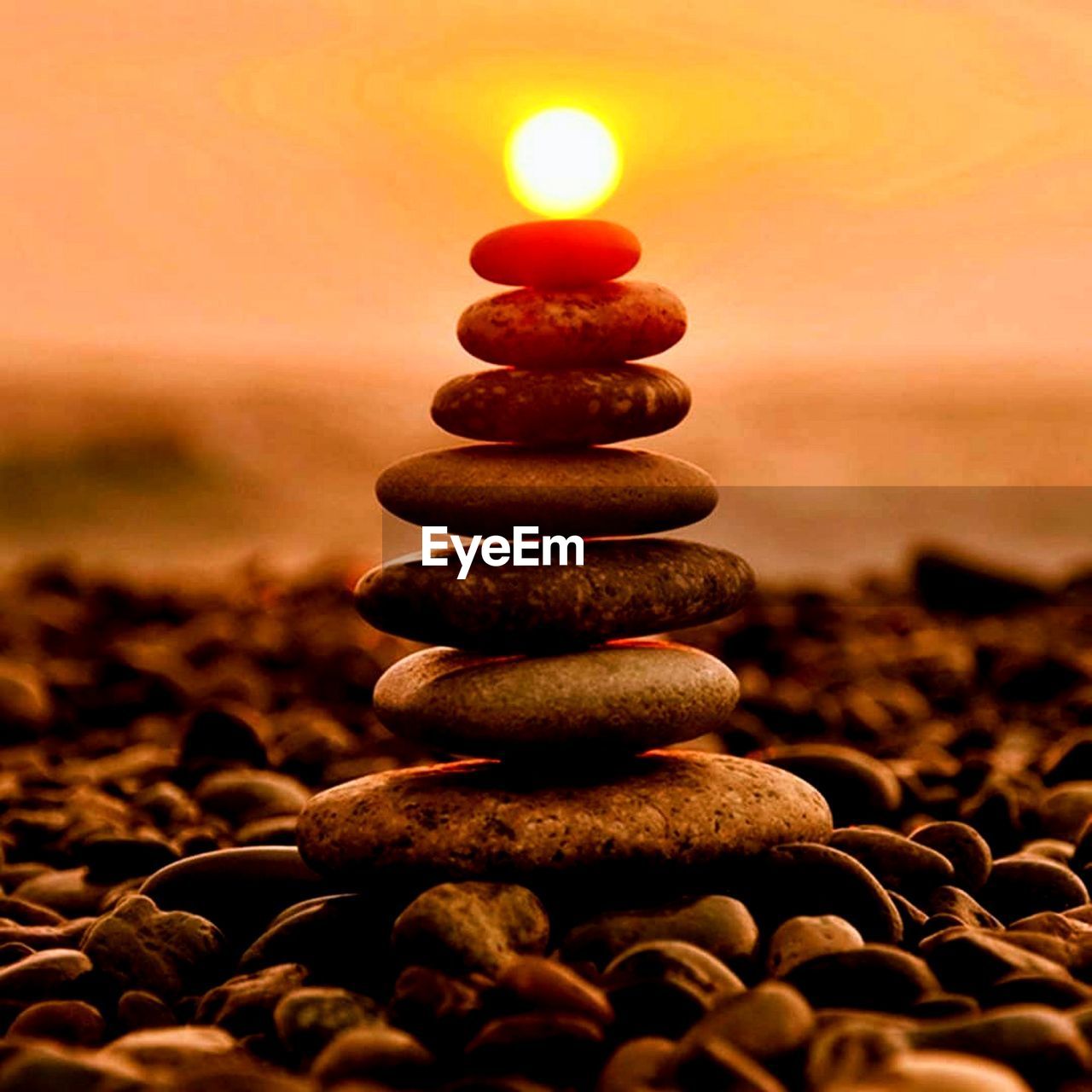 Close-up of stones stacked at shore during sunset