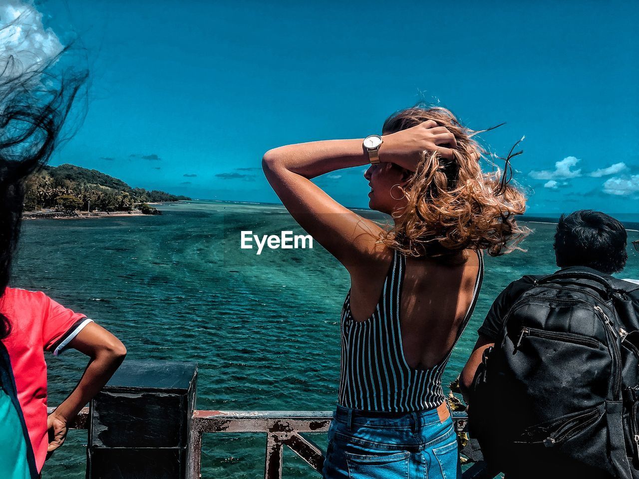 WOMAN STANDING IN SEA AGAINST BLUE SKY