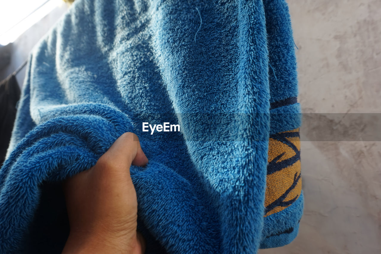 CLOSE-UP OF MAN HAND HOLDING BLUE UMBRELLA