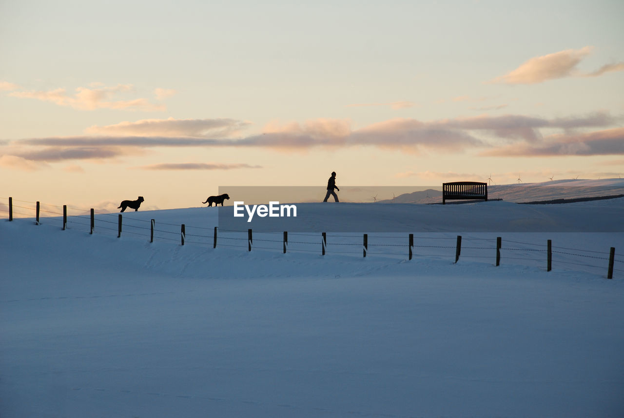 SILHOUETTE PEOPLE STANDING ON SNOW COVERED LANDSCAPE AGAINST SKY