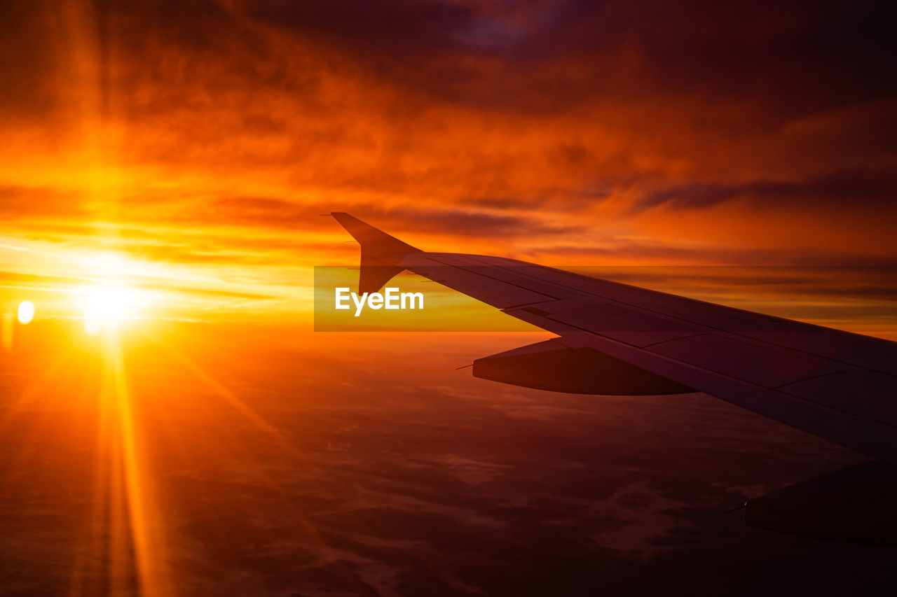 AIRPLANE FLYING OVER ORANGE SUNSET SKY