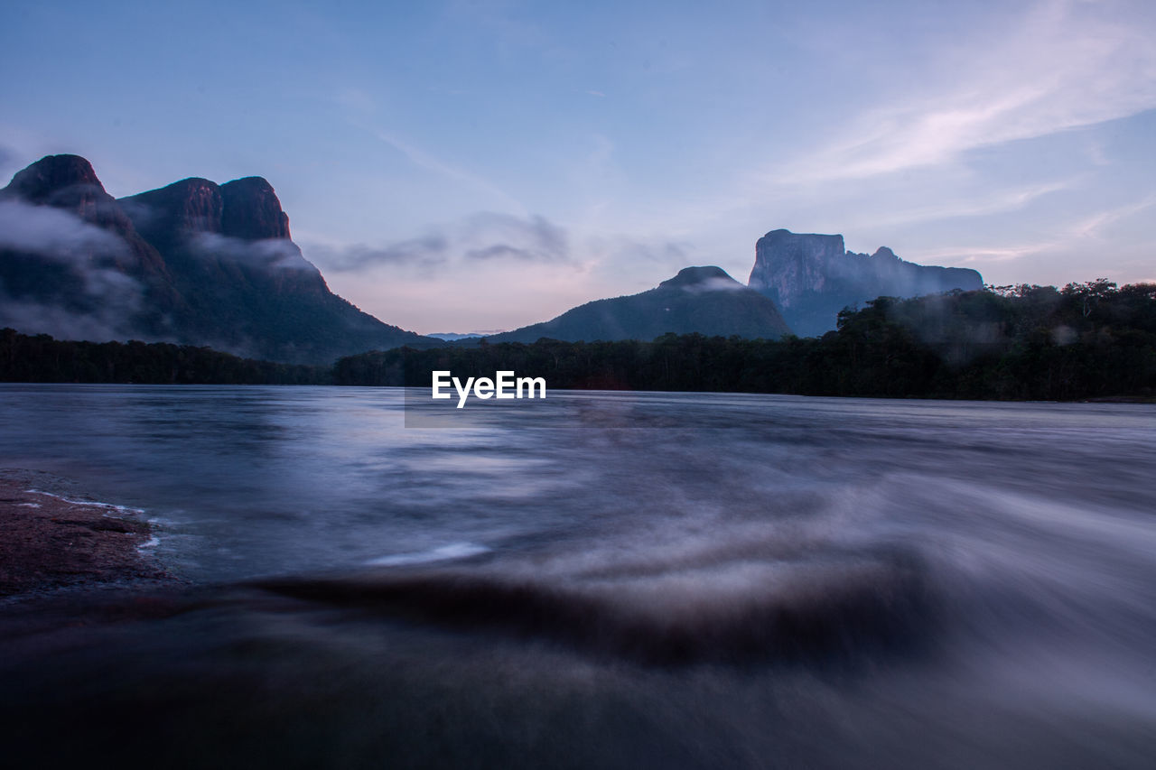 Longtime exposure of river in amazonia area at sunrise with typical tepui mountain in the background