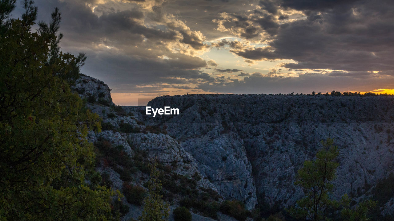 SCENIC VIEW OF MOUNTAINS AGAINST CLOUDY SKY