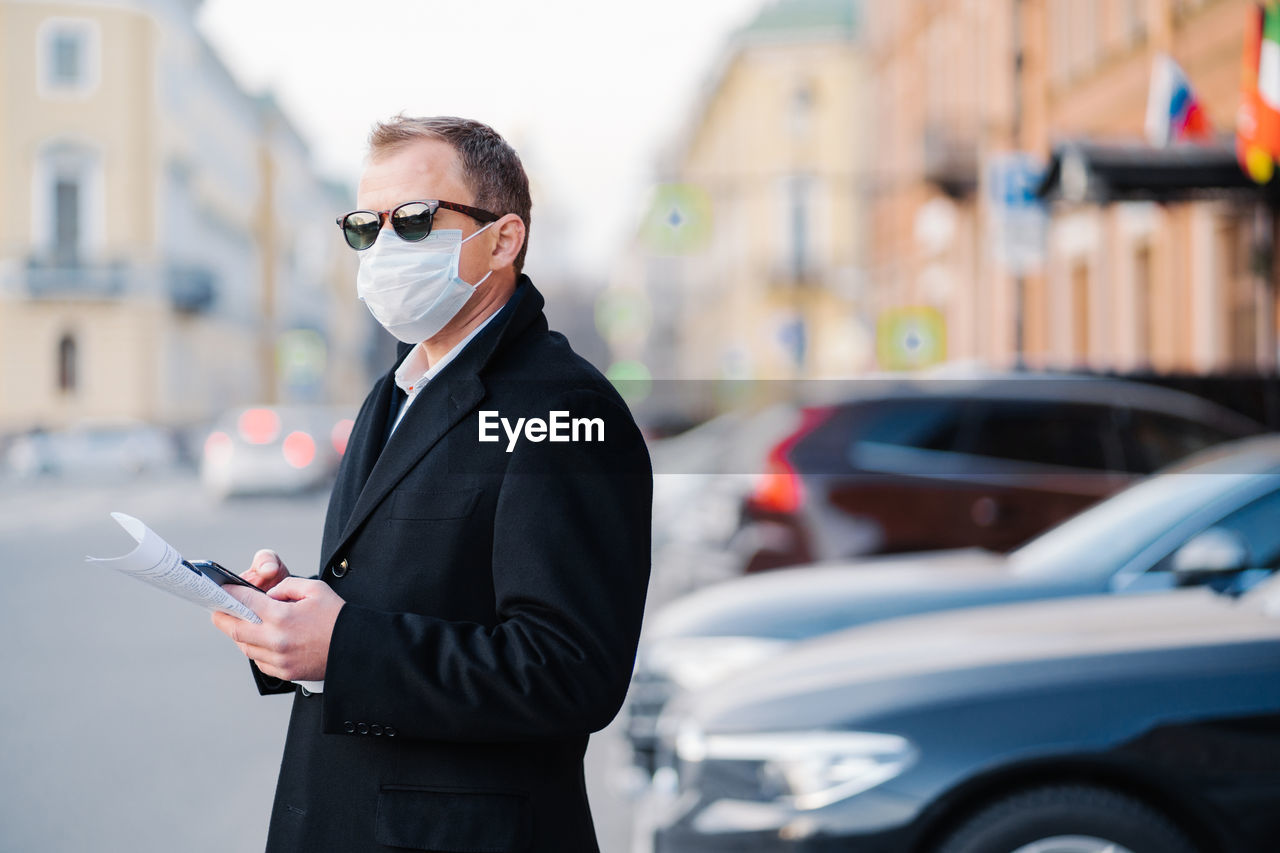 Side view of businessman wearing mask standing on street