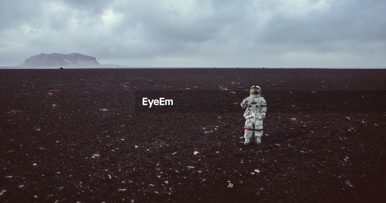 Full length of astronaut standing on field against sky