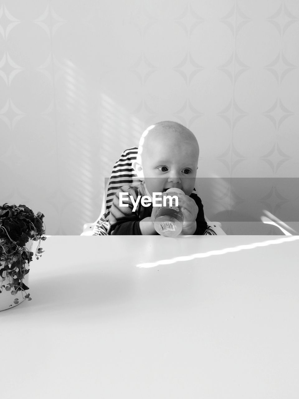 Cute baby drinking from bottle at home