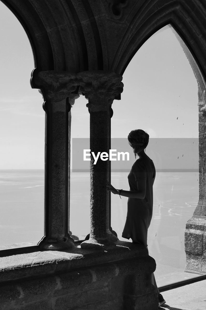 Woman standing in historic building against sky