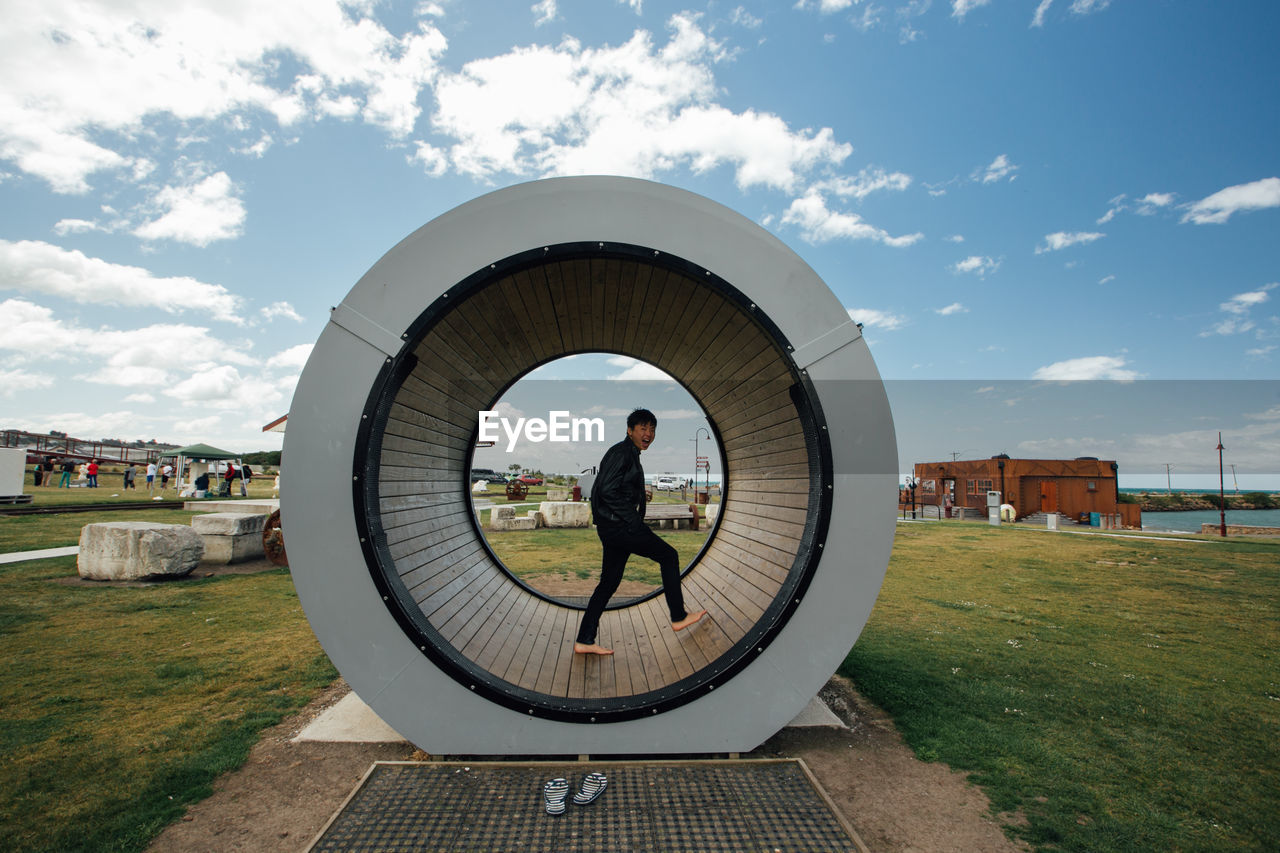 Side view of man walking in circular built structure on land against sky