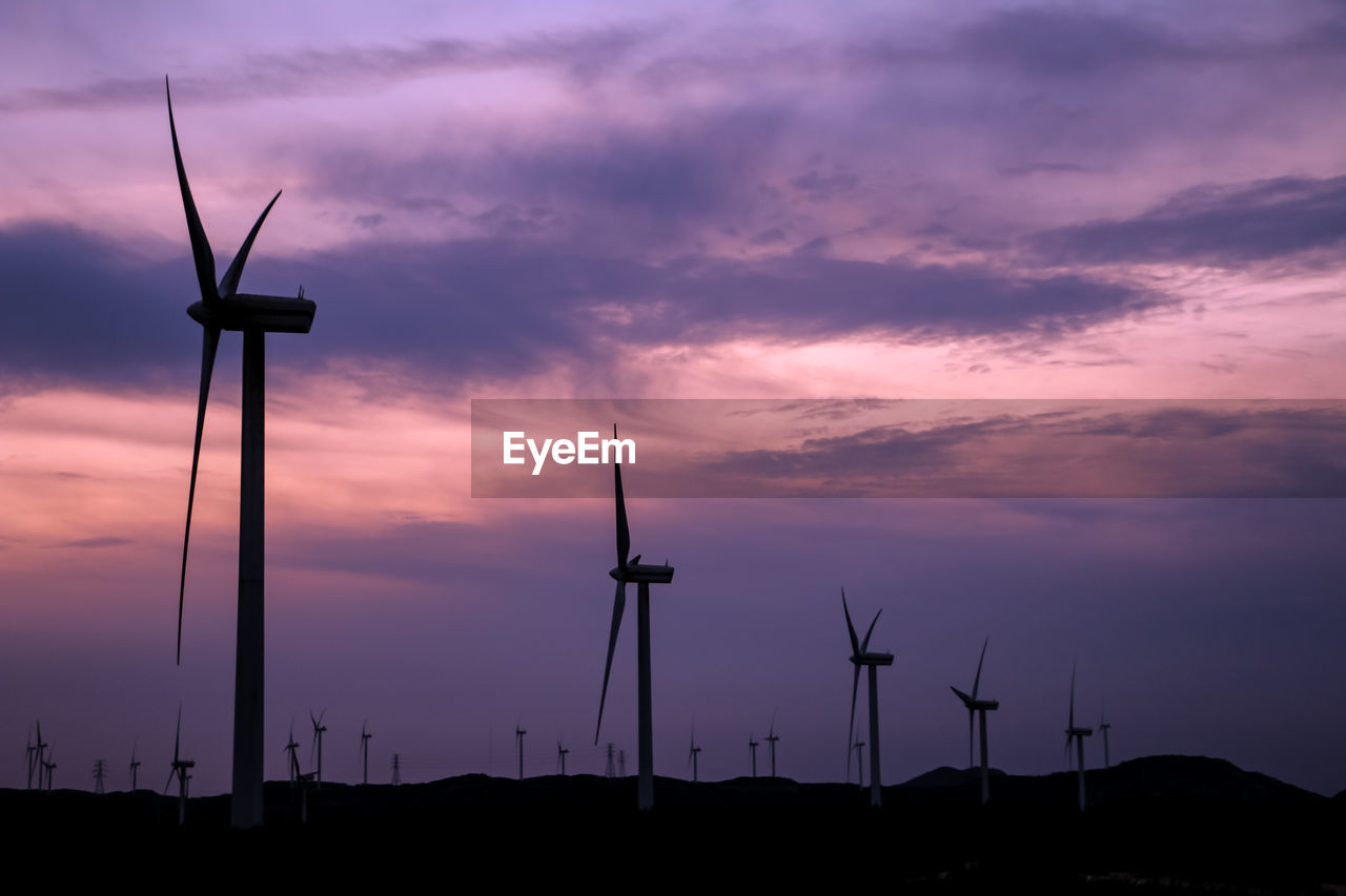 LOW ANGLE VIEW OF WIND TURBINE AGAINST SKY DURING SUNSET