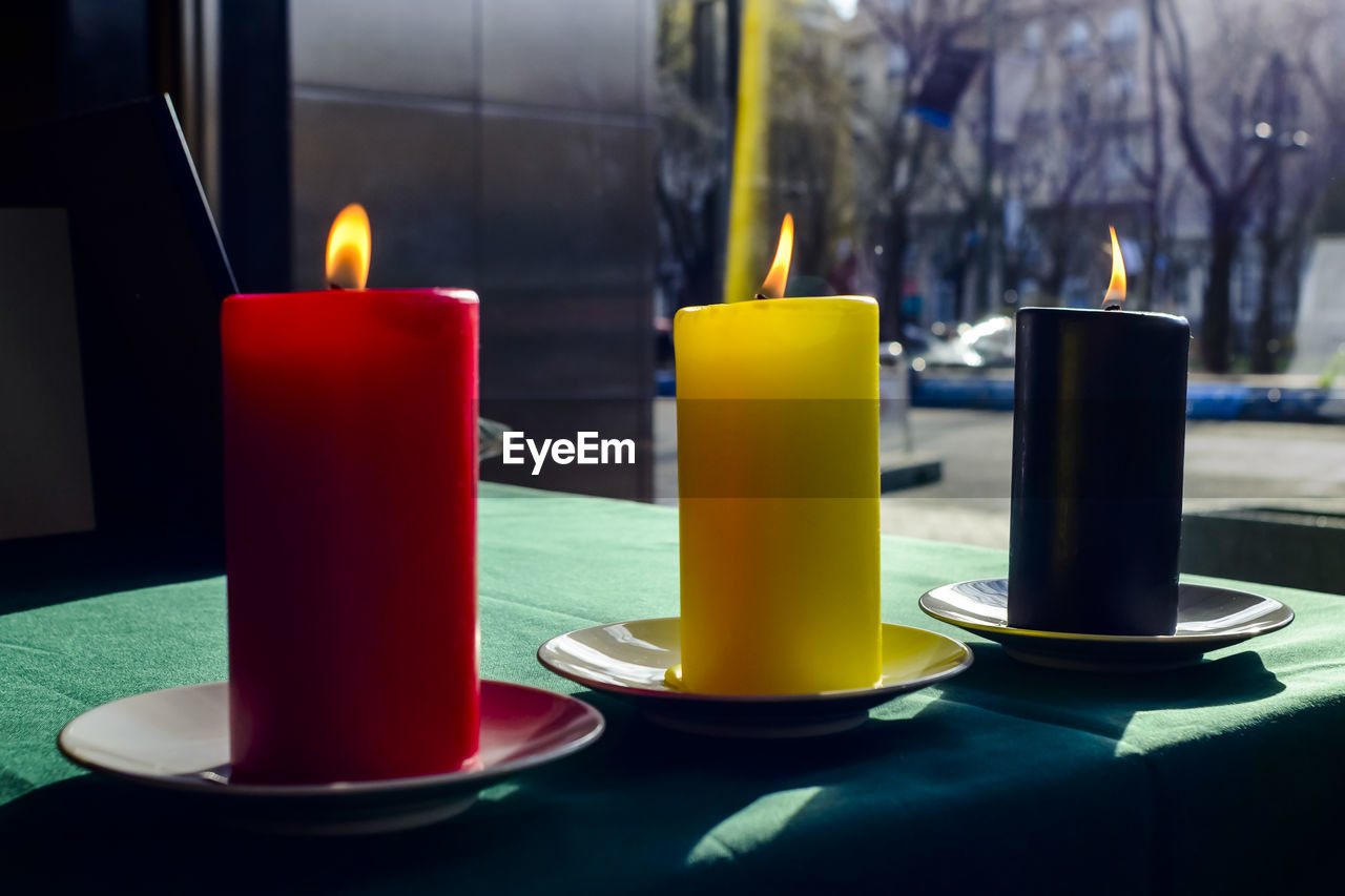 Lit candles symbolizing belgium flag on table at embassy building