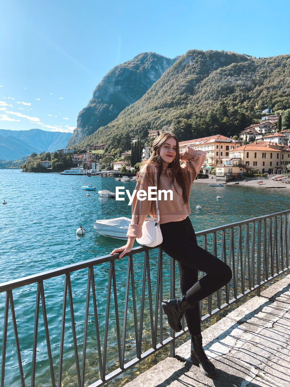 Full length of young woman standing by railing against mountain