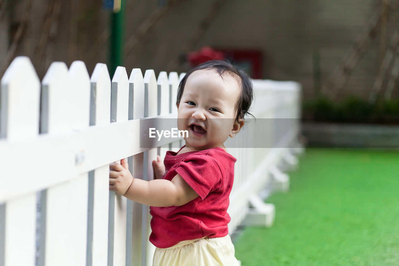 Portrait of cute girl smiling by fence