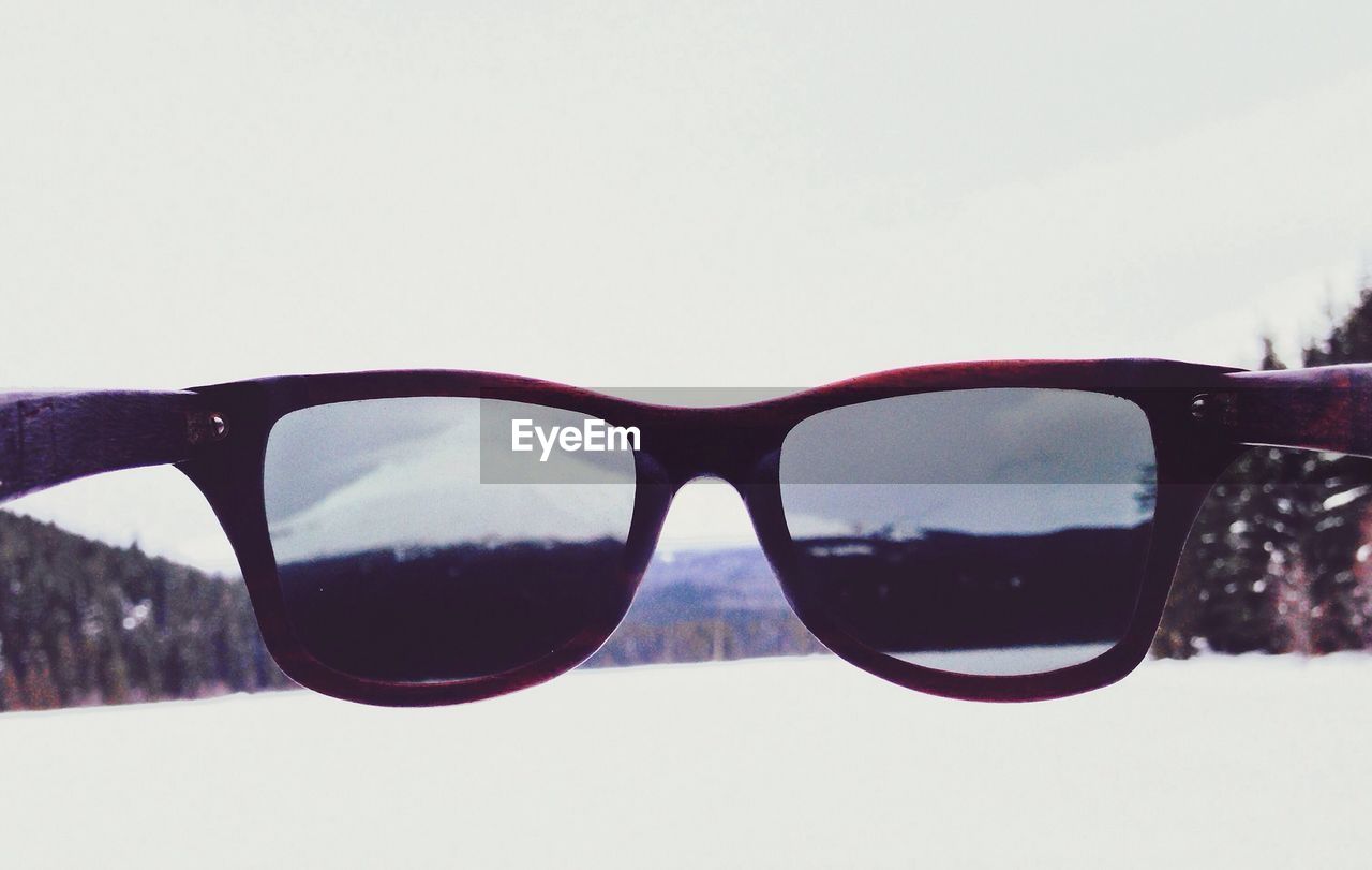 Close-up of sunglasses against snow covered landscape