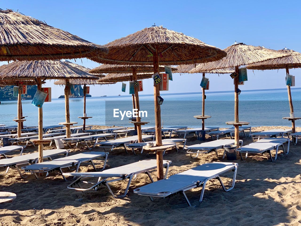 Deck chairs on beach against clear sky