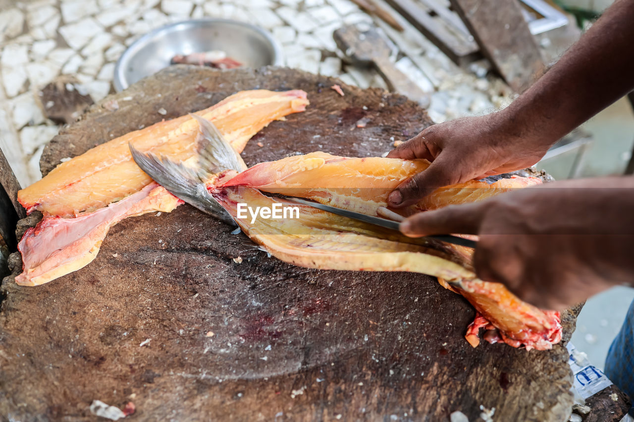 hand, food, food and drink, freshness, one person, adult, occupation, fish, men, animal, seafood, business finance and industry, outdoors, cooking, business, holding, high angle view, day, healthy eating, close-up, dish, raw food, meat, wood, wellbeing, market, fishing, working, preparing food