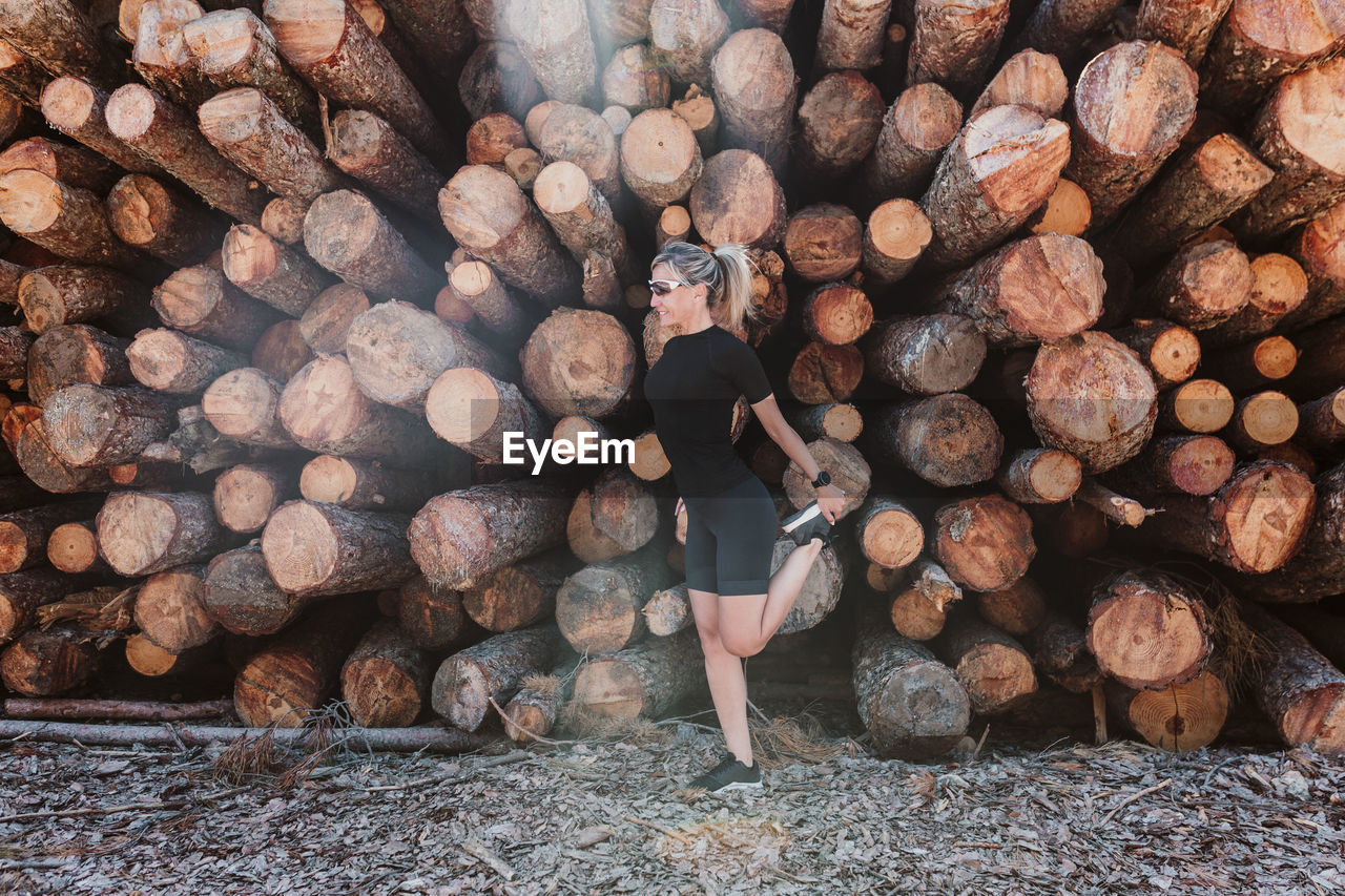 Woman against stack of logs