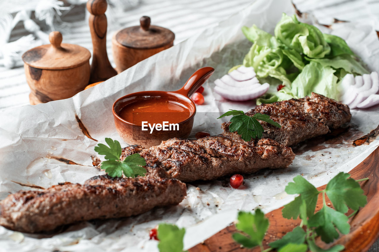 Kebab with sauce and greens on a plate