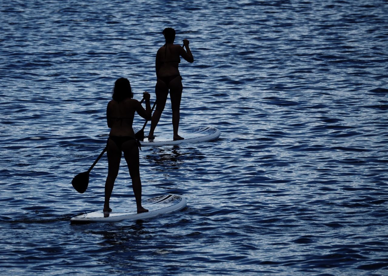 Silhouette people in sea