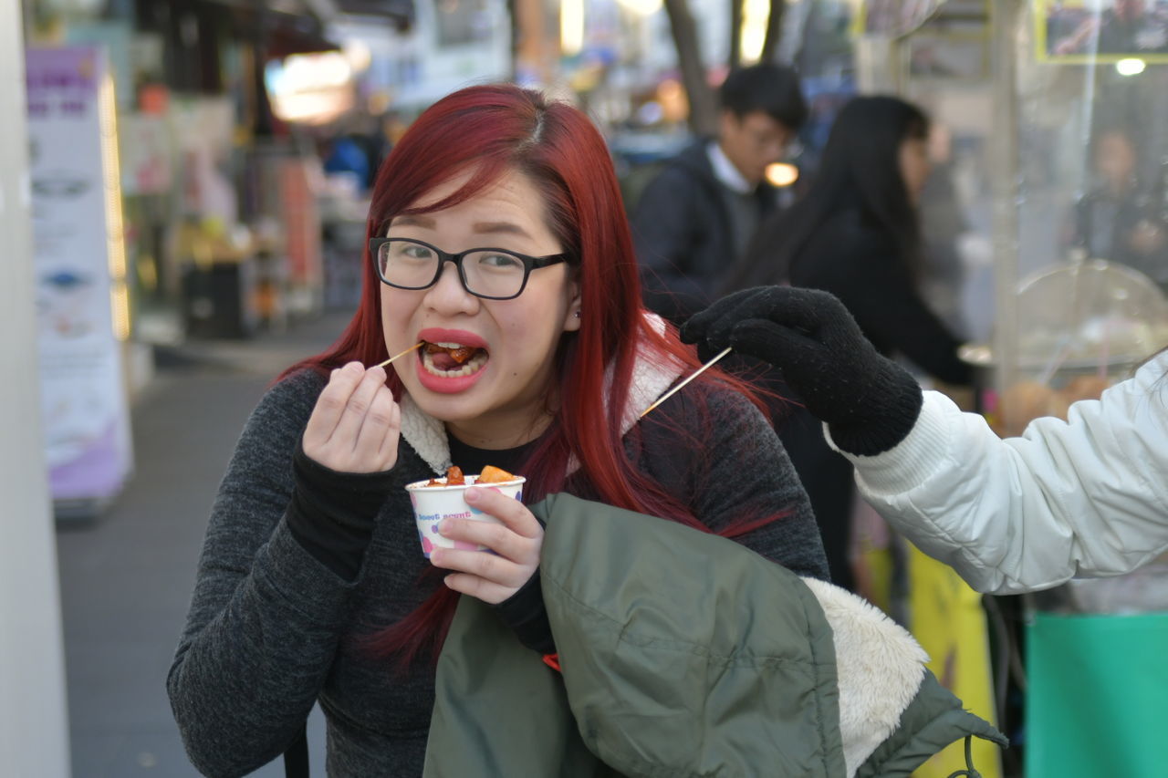 CLOSE-UP OF YOUNG WOMAN EATING IN PARK