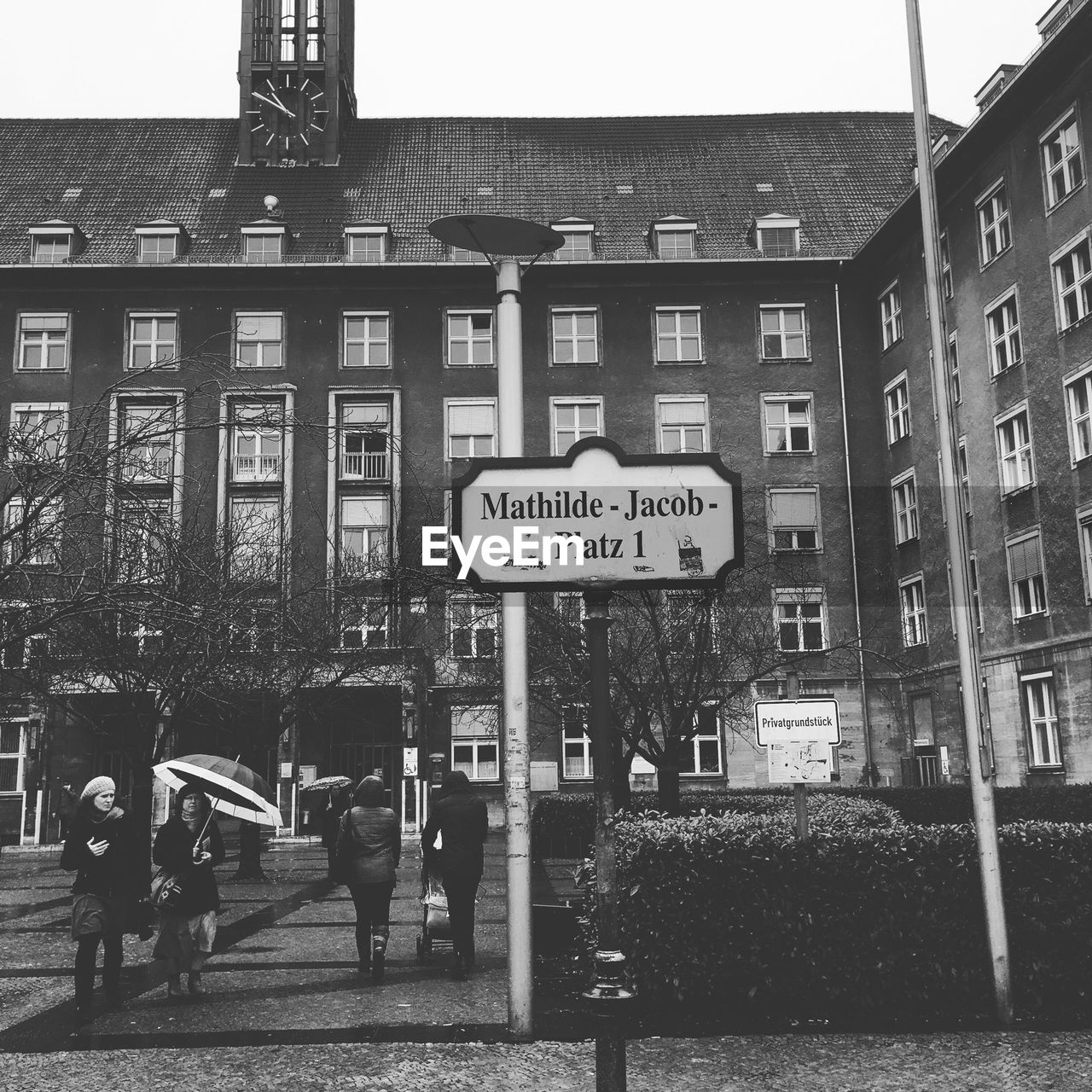 People walking on walkway against burgeramt rathaus tiergarten
