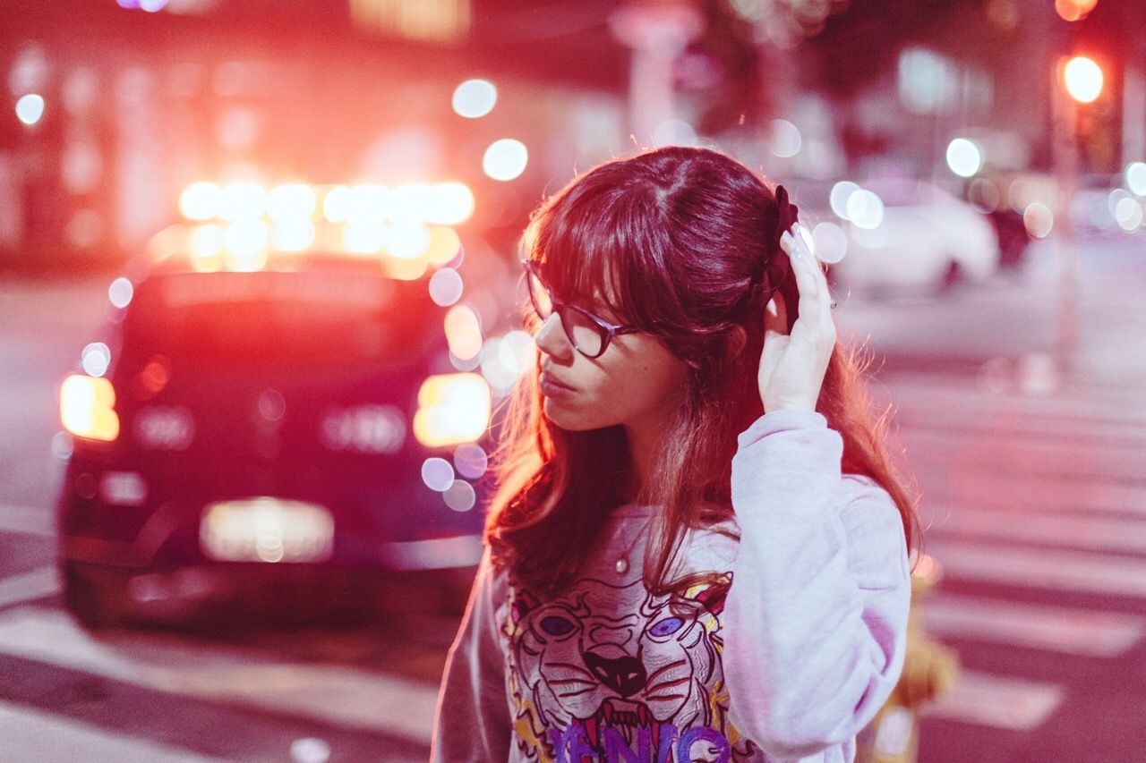 Woman with hand in hair walking on city street at night