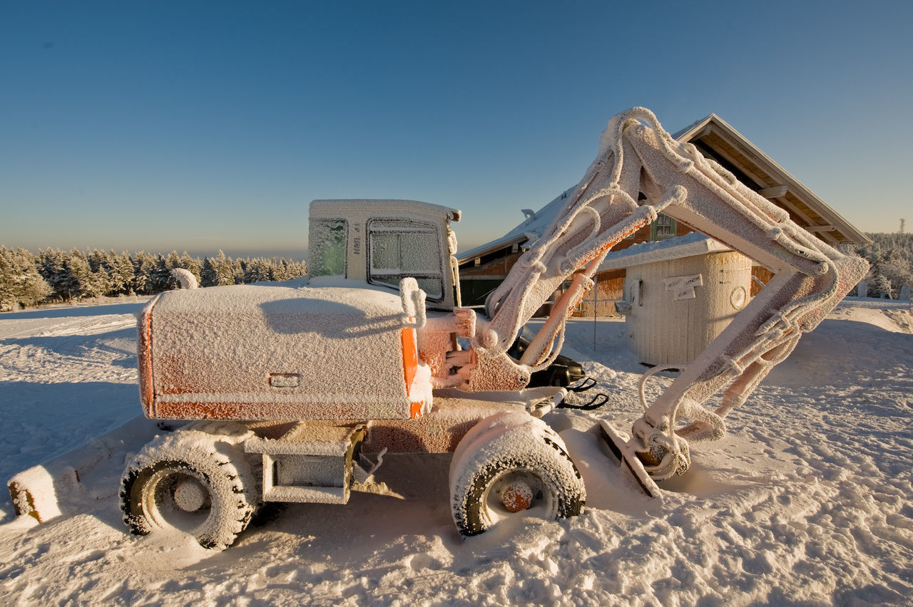 Snowy excavator standing in winter landscape