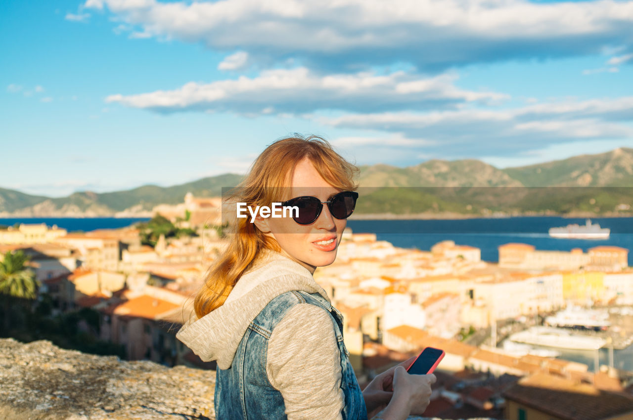 Portrait of young woman with townscape in background