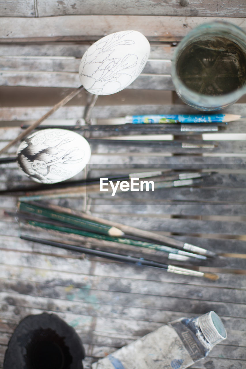 Directly above shot of eggs and painting equipment on wooden table