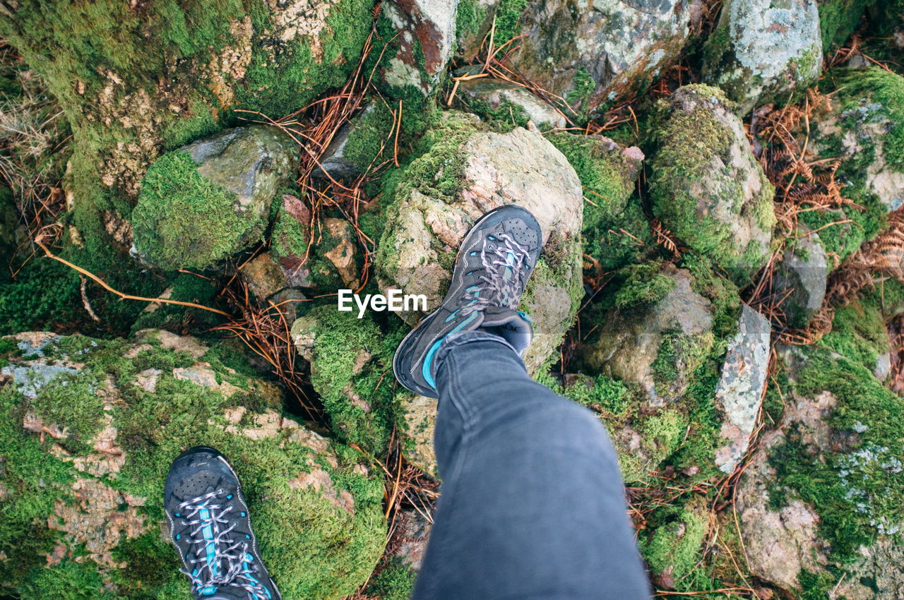 Low section of man standing on moss covered stones