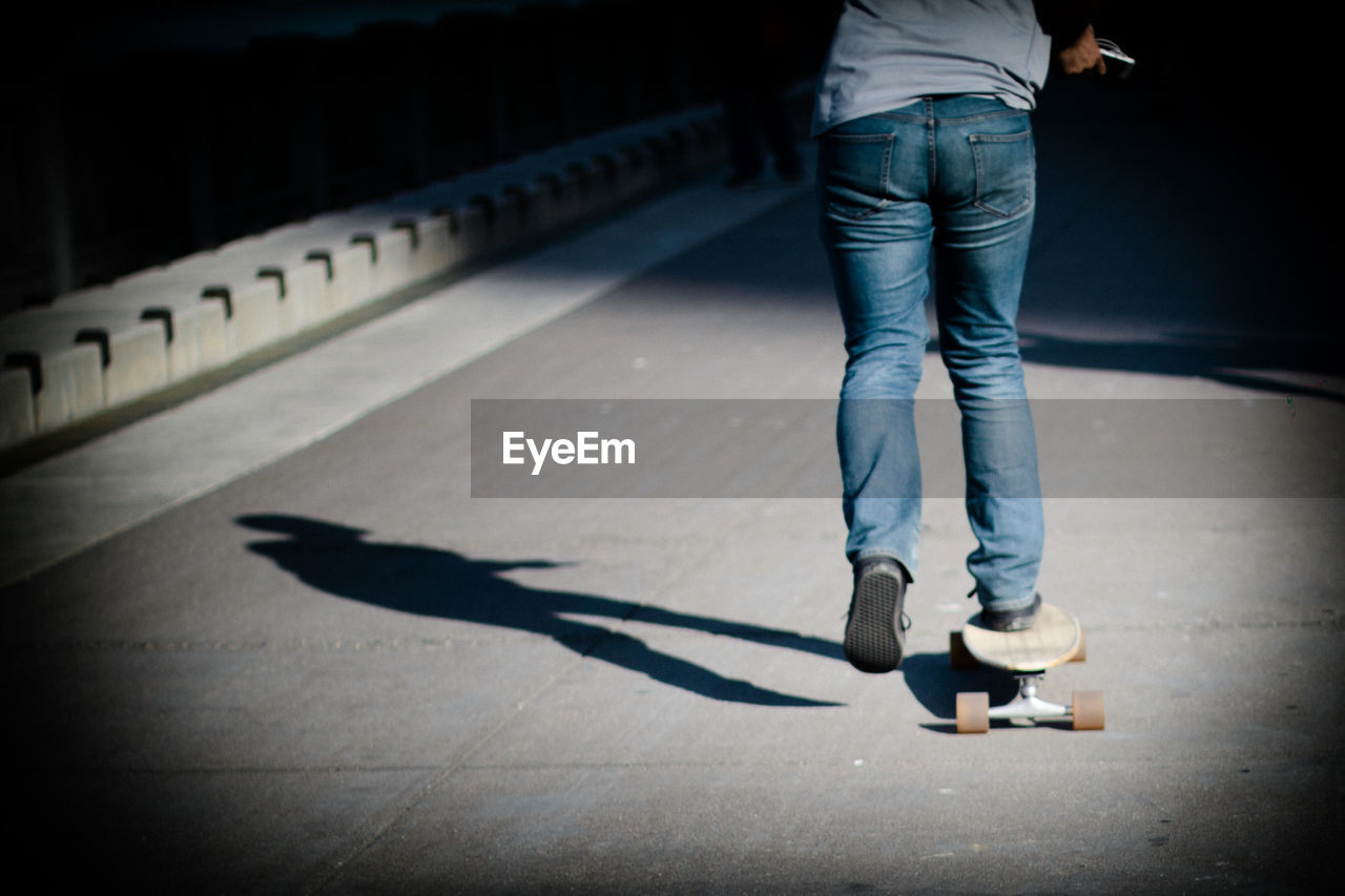 Rear view low section of skateboarding on road