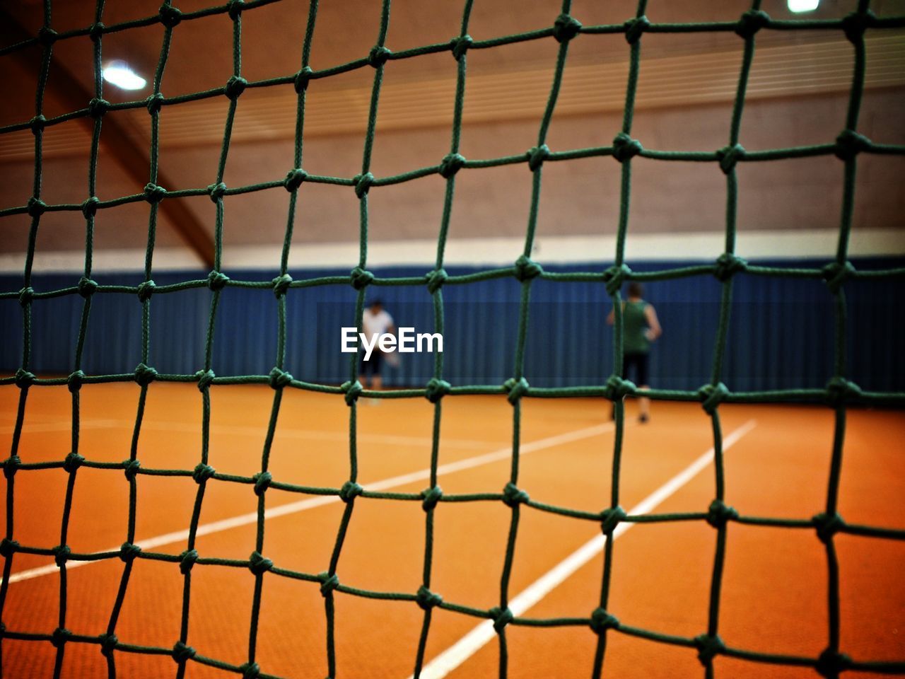 Men playing at tennis court seen through net