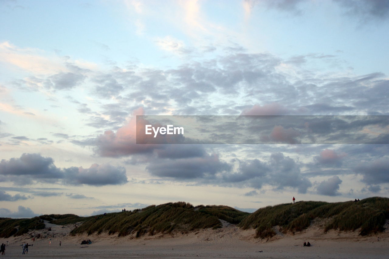 Scenic view of hill against cloudy sky at dusk