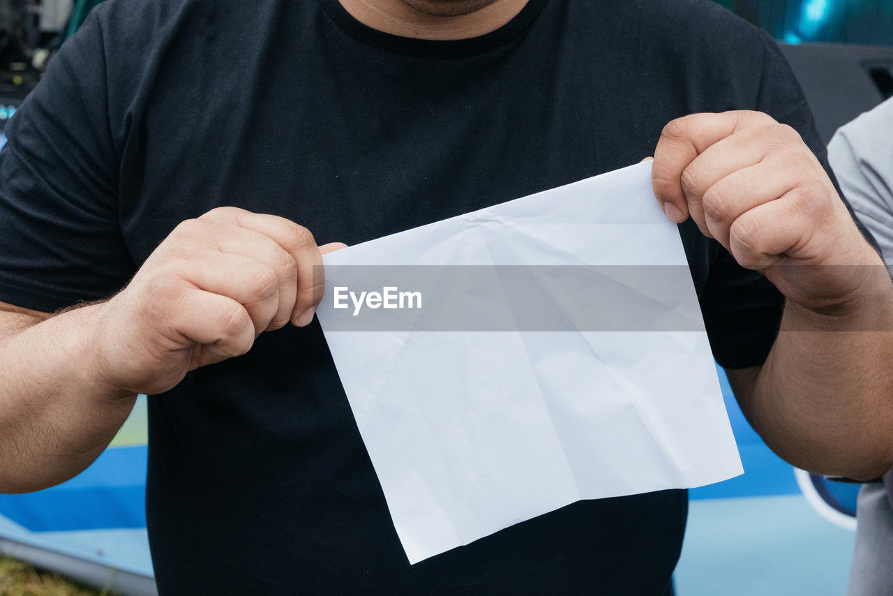 men, one person, holding, adult, clothing, front view, person, hand, paper, business, midsection, t-shirt, close-up, casual clothing, occupation